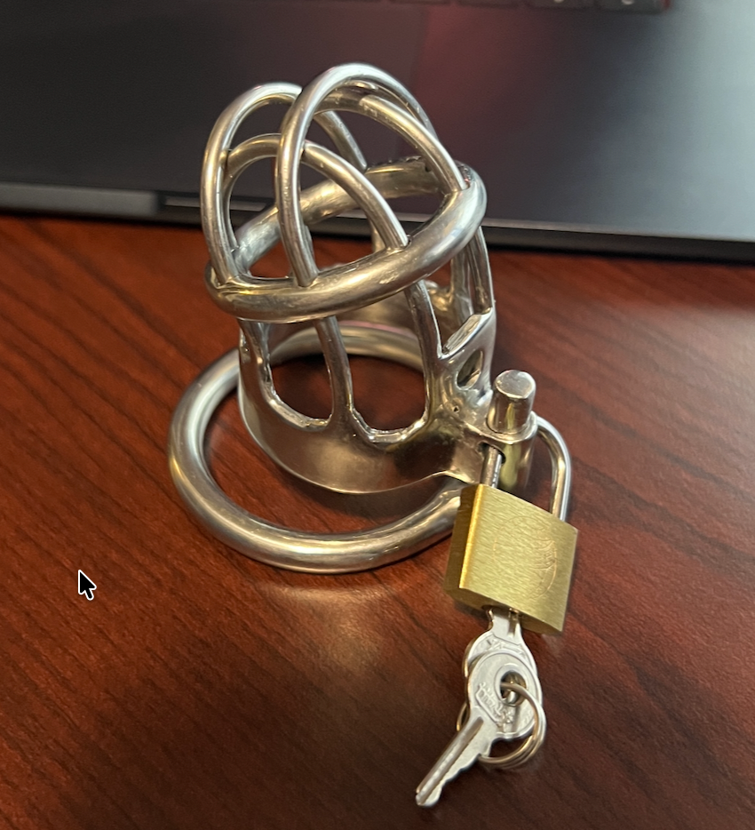 The actual metal chastity cage with its lock and key